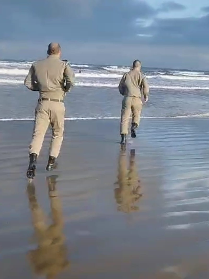 Policiais militares adentram o mar para salvar homem 